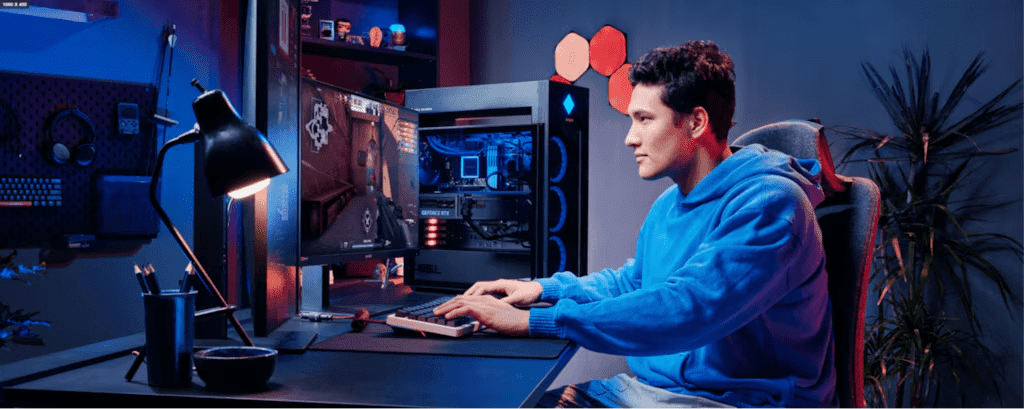 Una persona con sudadera azul sentada frente a una configuraci&oacute;n gaming con una caja de PC abierta que muestra componentes internos, iluminada por luces azules y rojas en una habitaci&oacute;n oscurecida con decoraciones de pared hexagonales