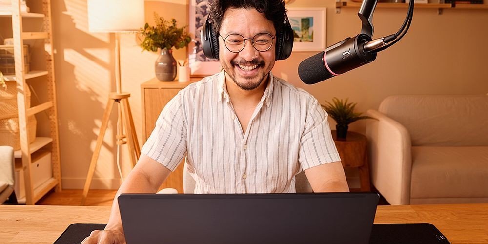 Creador de contenido grabando podcast o transmitiendo desde casa con equipamiento profesional HyperX, incluyendo micr&oacute;fono de brazo articulado y aud&iacute;fonos, utilizando laptop HP en un ambiente hogare&ntilde;o , ideal para streaming, podcasting y gaming.